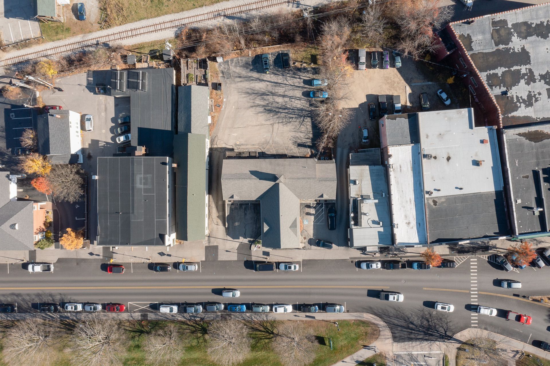 Aerial view of a street with cars, buildings, and a parking lot.