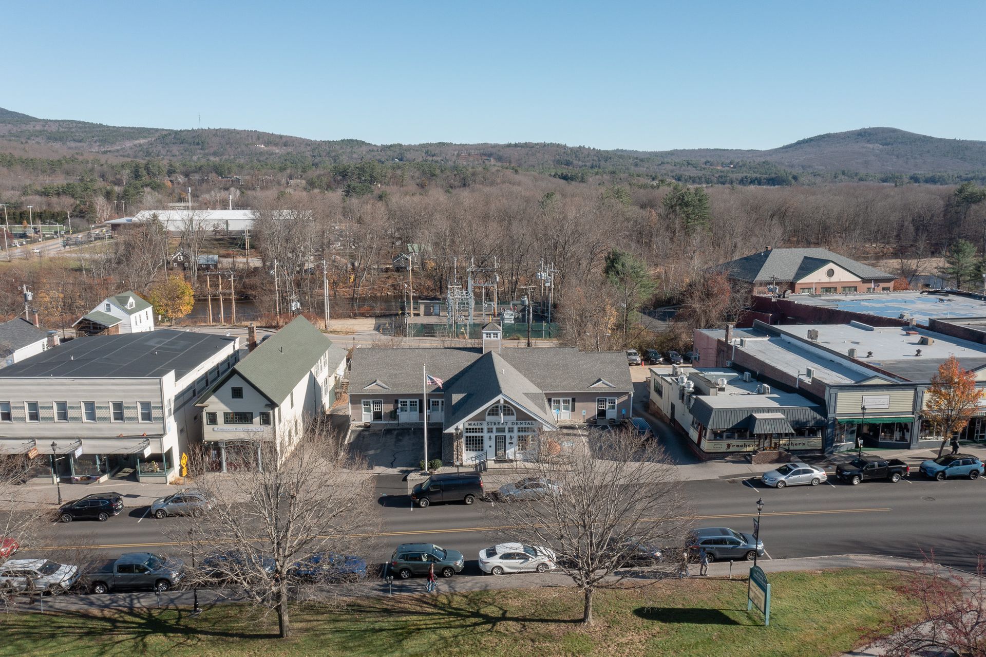 Townscape with buildings and cars on a street with trees and a distant mountain. Sunny day.