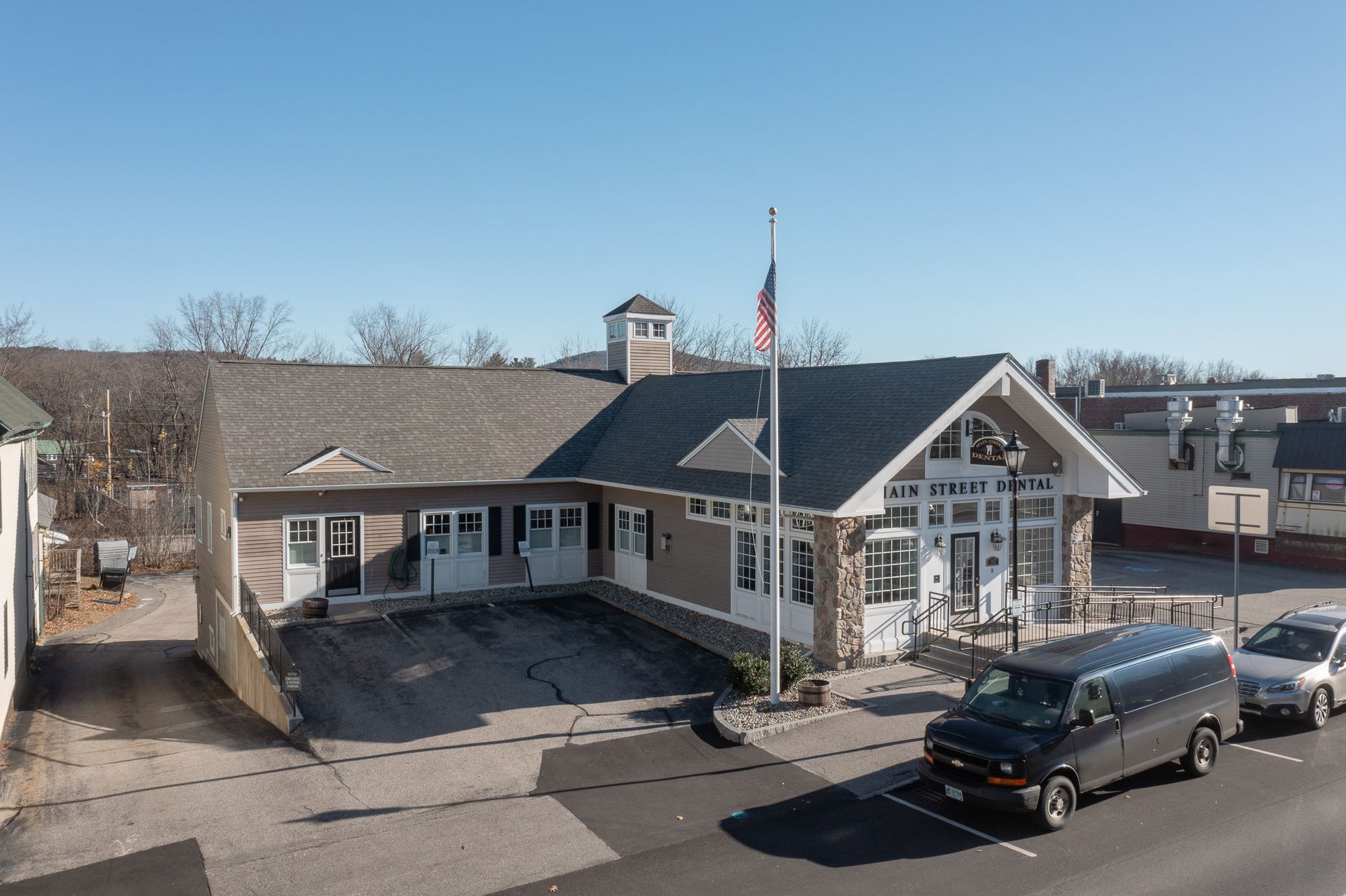 Heartland Dental building with US flag. Cars parked in front. Clear blue sky.