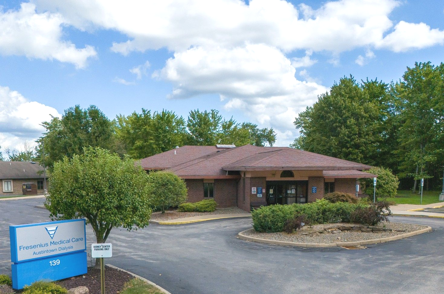 Fresenius medical care building in austintown ohio with sign in front, trees and blue sky.