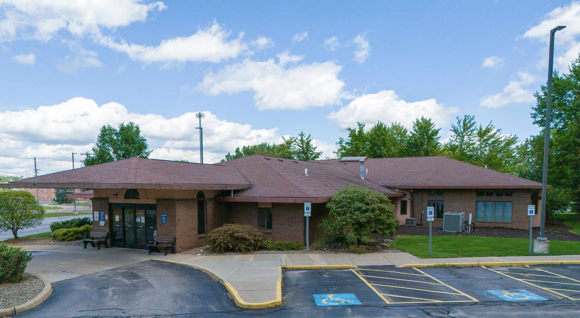A single-story fresenius medical care building in austintown ohio with brown roof, accessible parking spaces, and a cloudy sky.