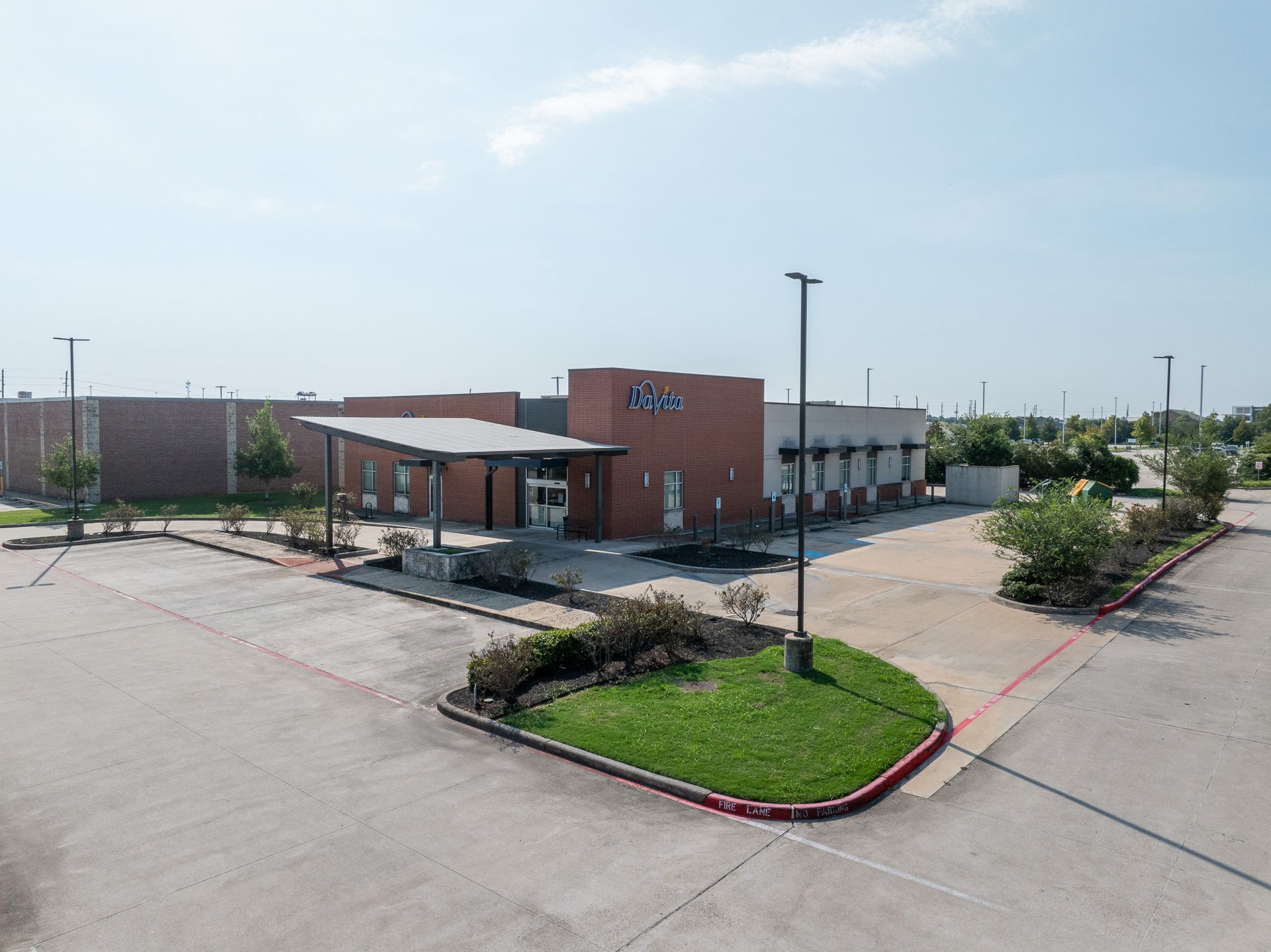 Exterior view of a modern davita dialysis building with a covered entrance. Brightly lit parking lot.