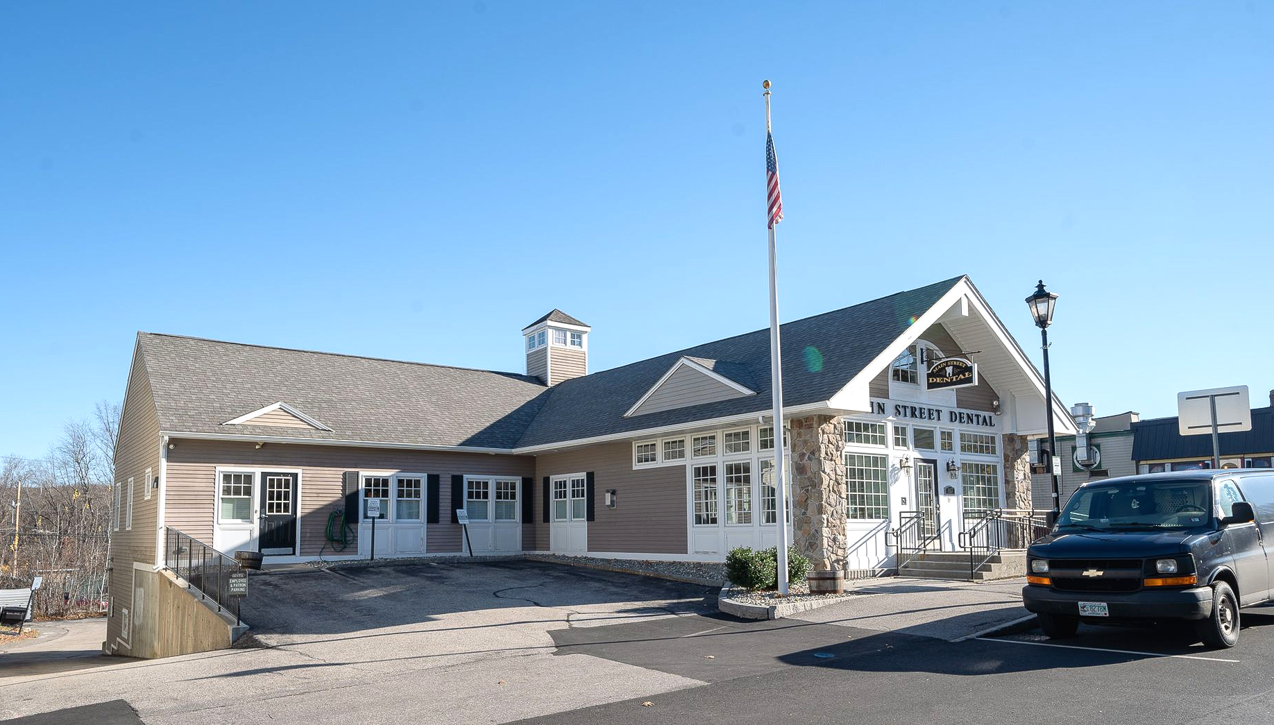 Heartland Dental building with stone accents and a flagpole. A van is parked in front.