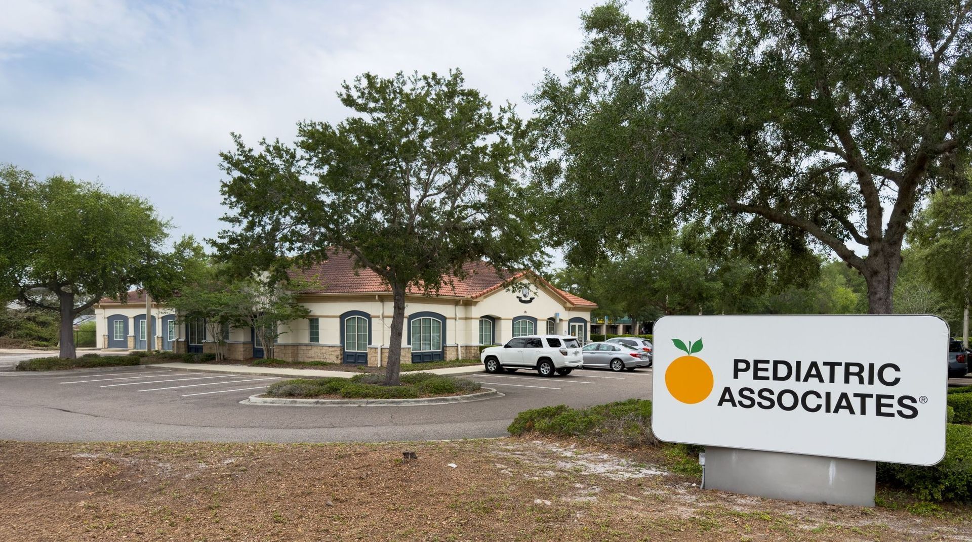 Pediatric Associates clinic building in Deltona, FL with sign in front, surrounded by trees and a parking lot