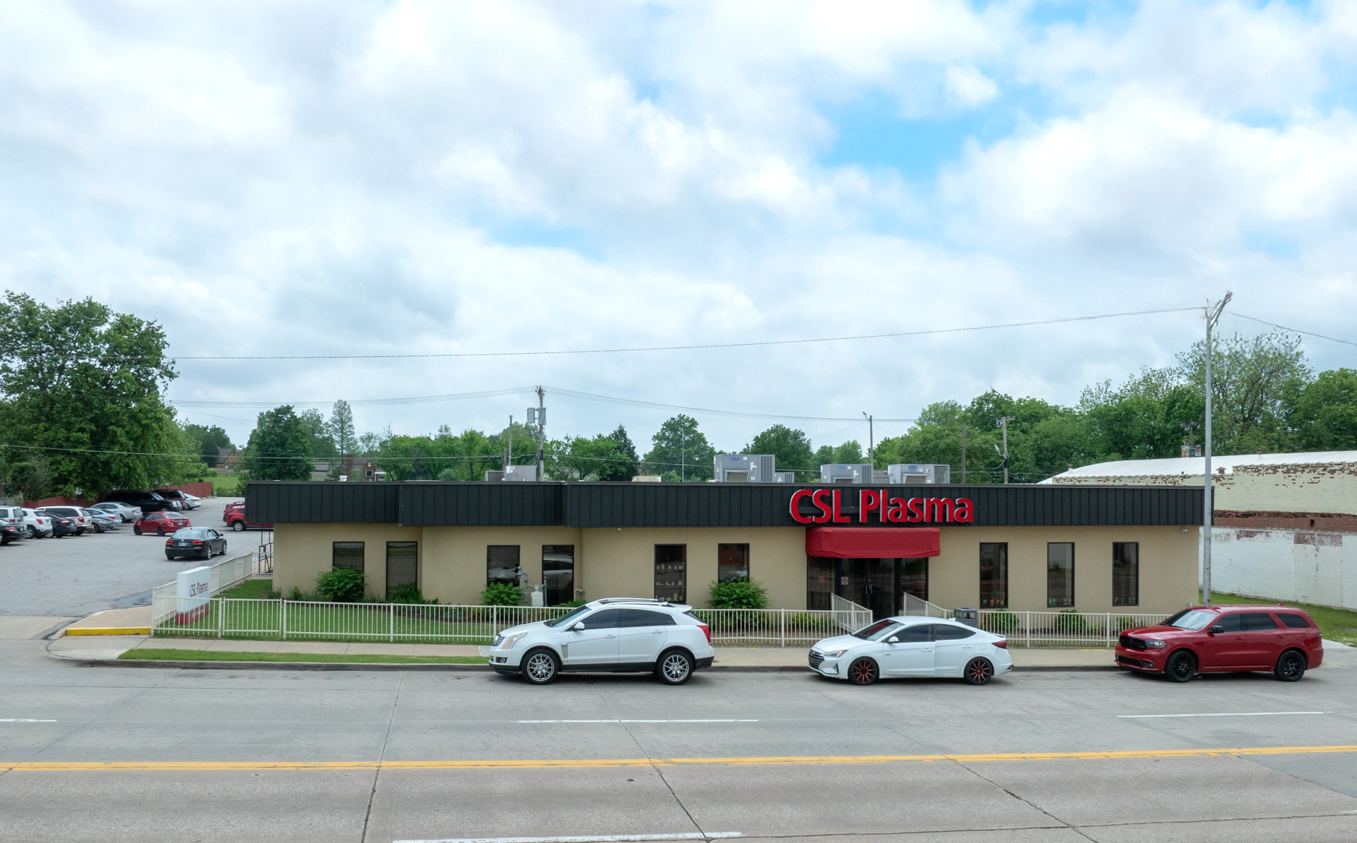 A row of cars are parked in front of a CSL Plasma building.
