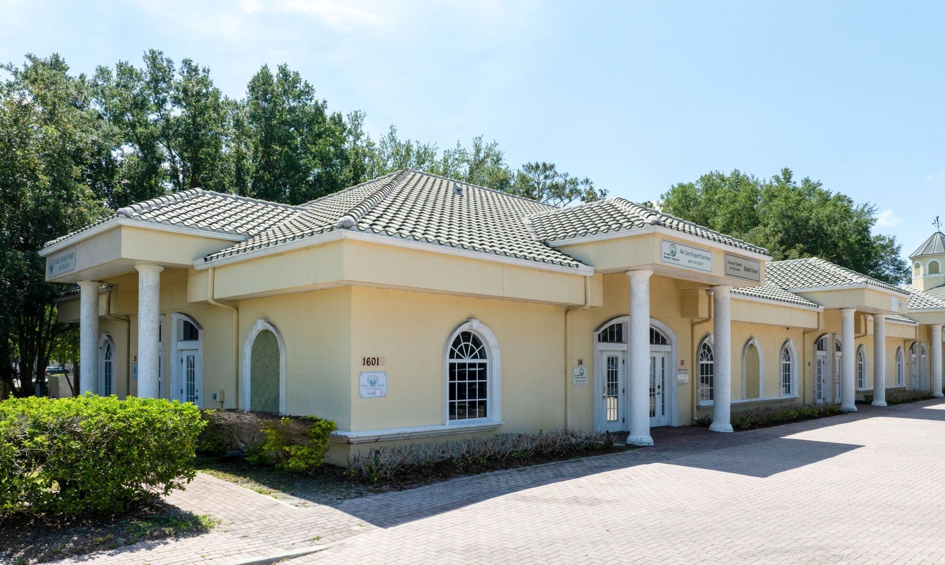 Pediatric Associates single-story beige building in Orlando, FL with arched windows and a tiled roof beside a paved driveway, surrounded by trees
