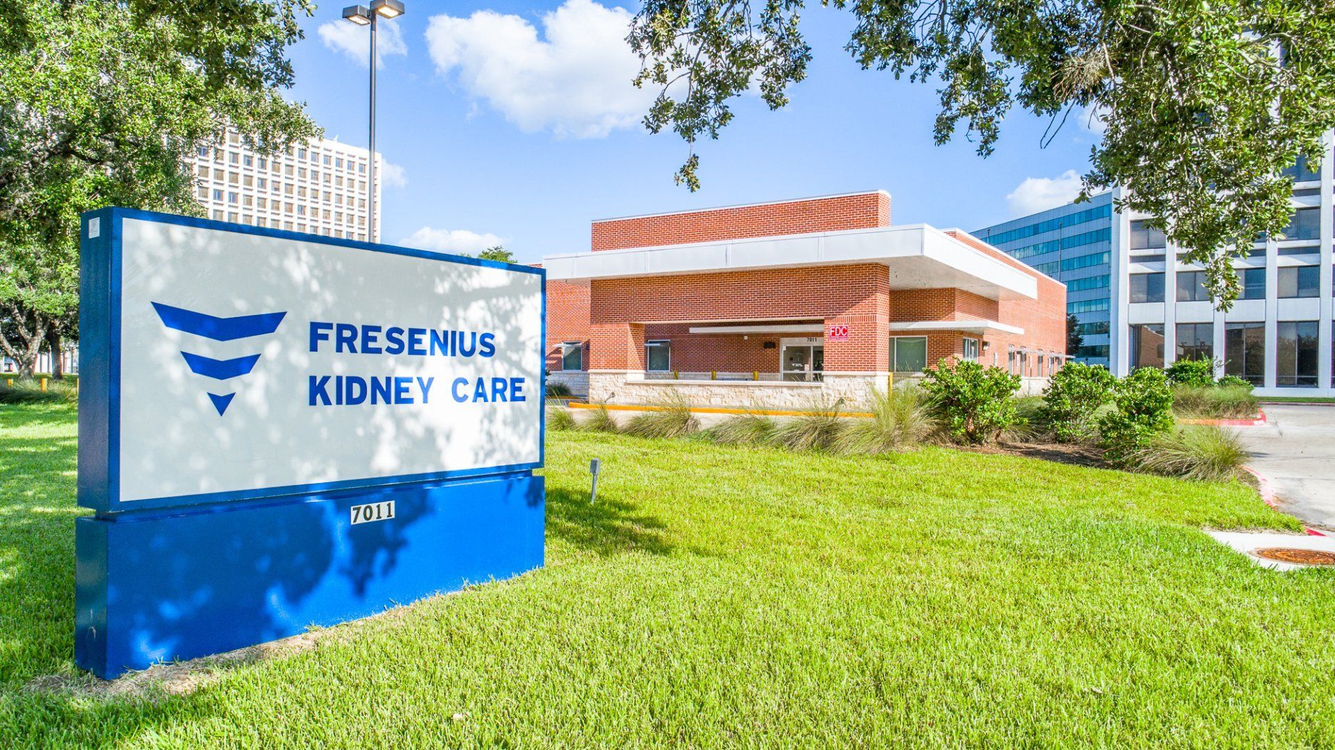 A large blue and white sign is in front of a large building.