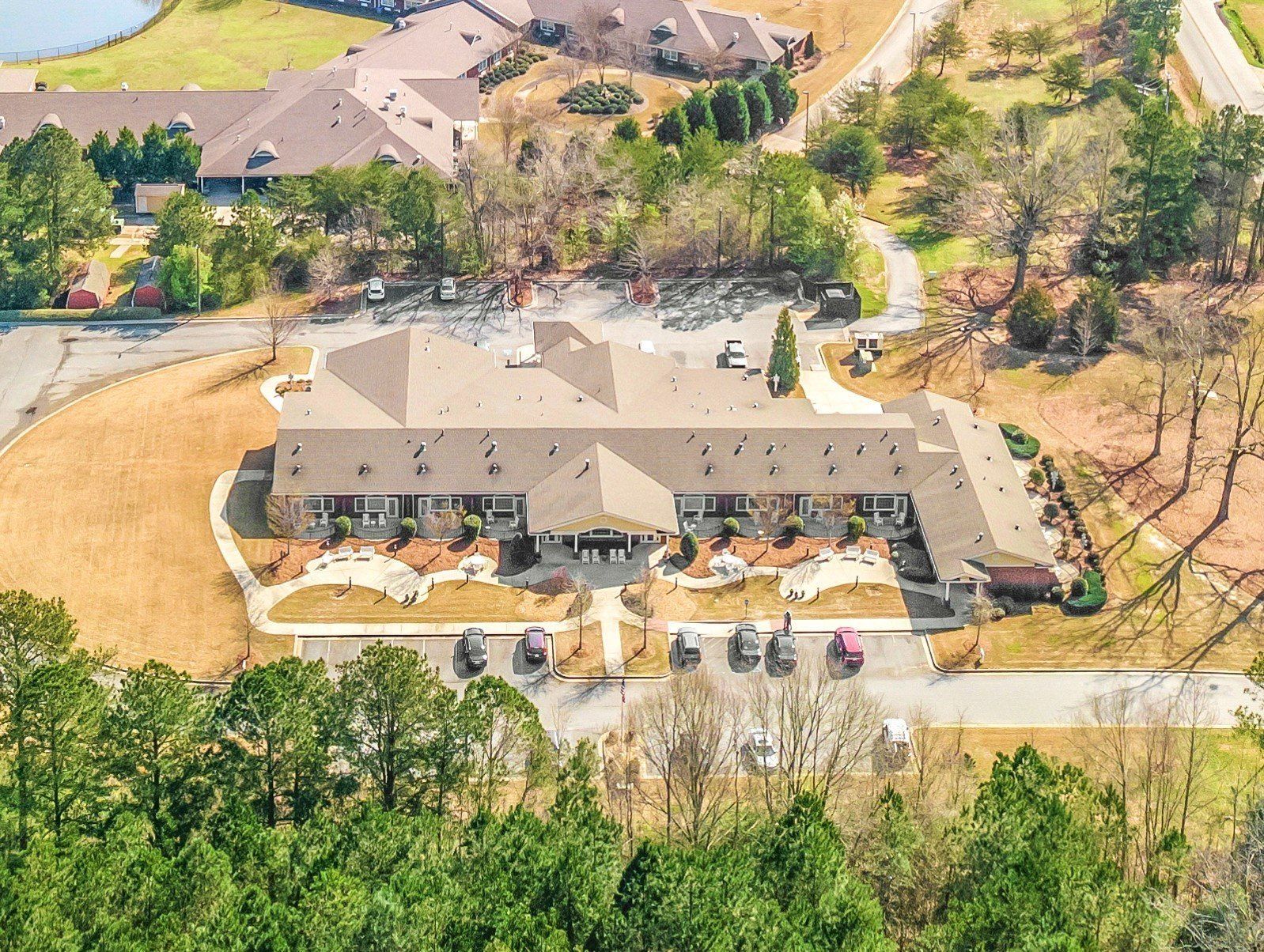 An aerial view of a large hospice building surrounded by trees and a lake.