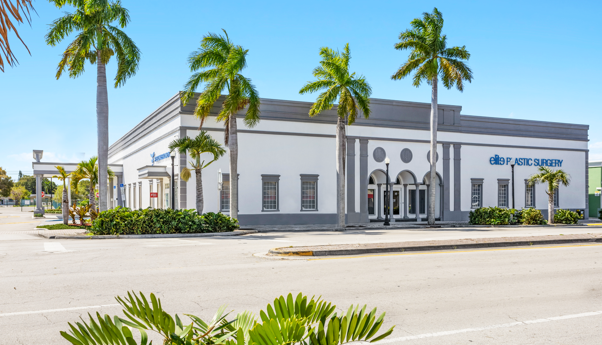 A white building with palm trees in front of it