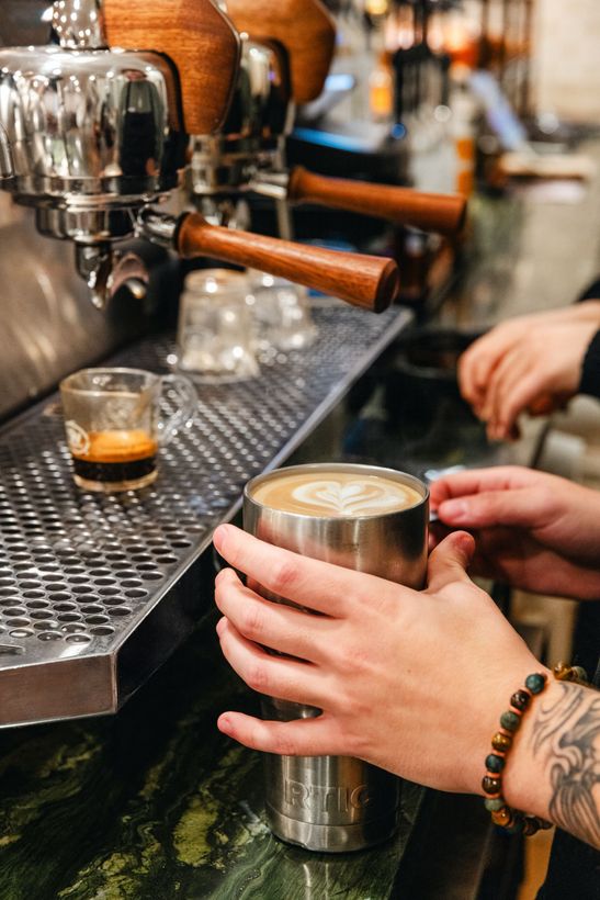 A man is making a cup of coffee in a coffee shop
