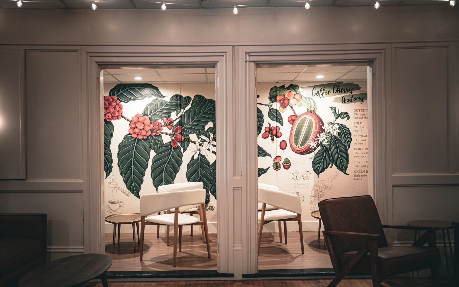 A room with tables and chairs and a mural on the wall.