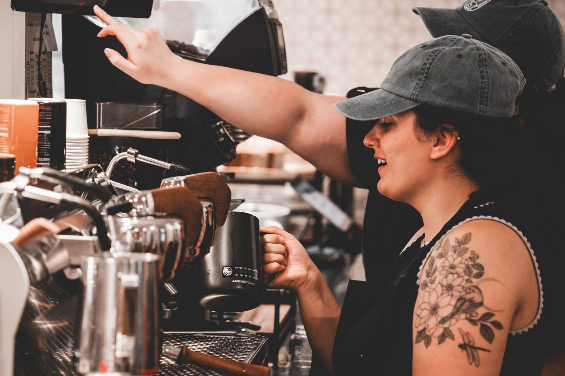 A woman is standing in front of a coffee machine in a restaurant.