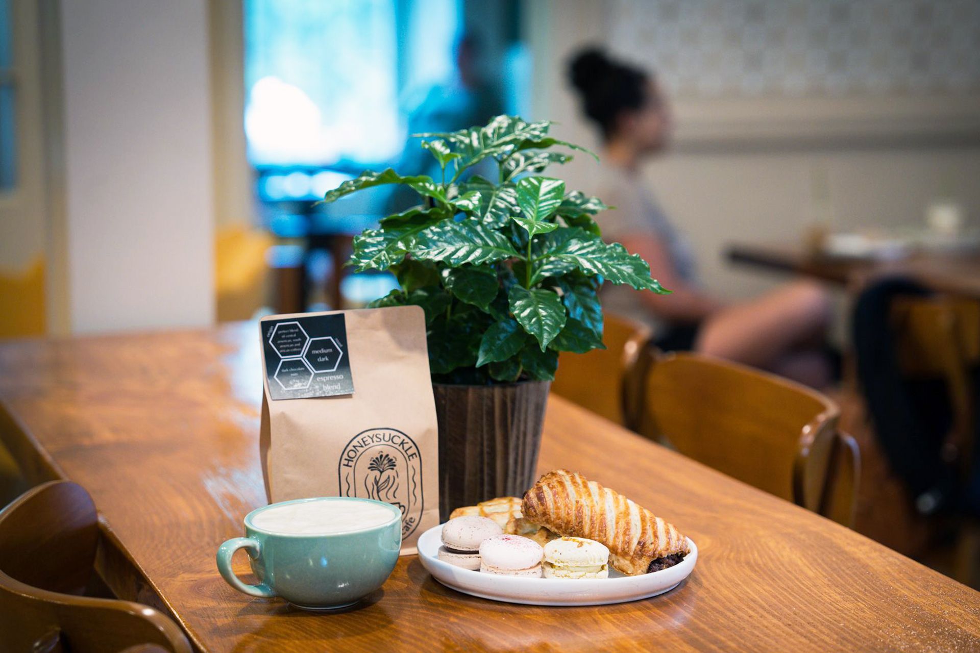 A table with a cup of coffee , croissants , and a plant on it.