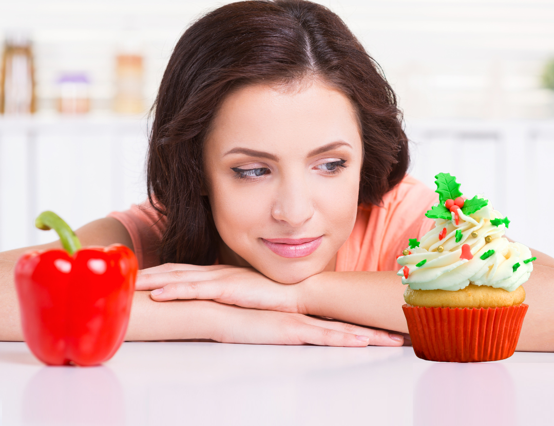 Woman choosing between a red pepper or a cupcake