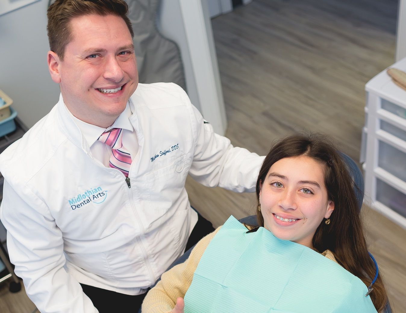 Photo of dentist with teen  in dental chair