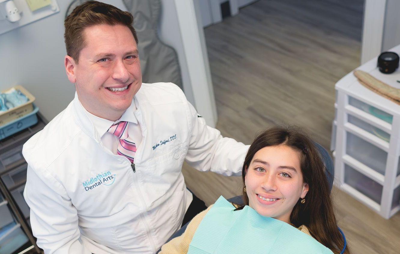 Teen in dental chair with doctor seated beside her