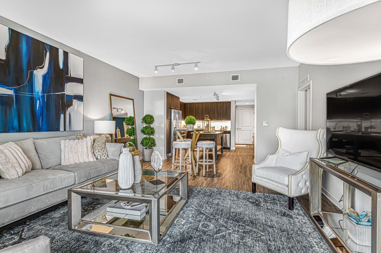 Open-concept living room at Olympus Harbour Island, offering apartments in Tampa, FL, with gray sofa, glass coffee table, and kitchen island.