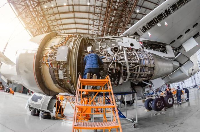 A man is working on the engine of an airplane in a hangar.