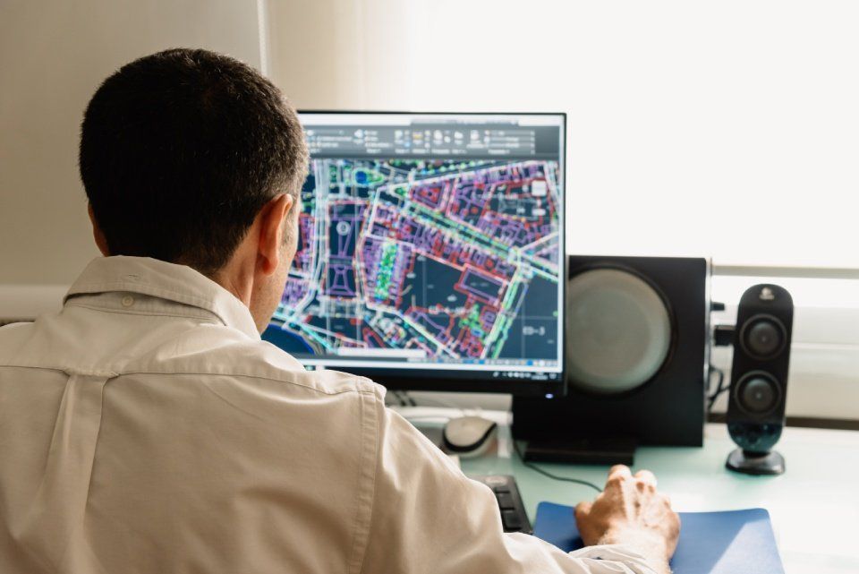 A man is sitting at a desk looking at a computer screen.
