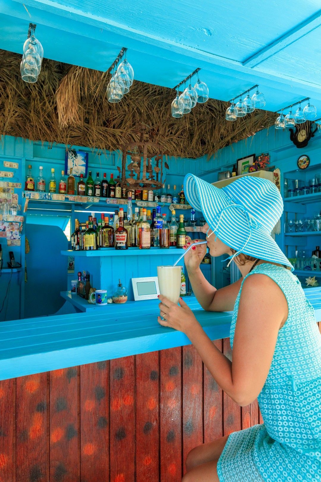 Una donna è seduta al bar e beve un frullato