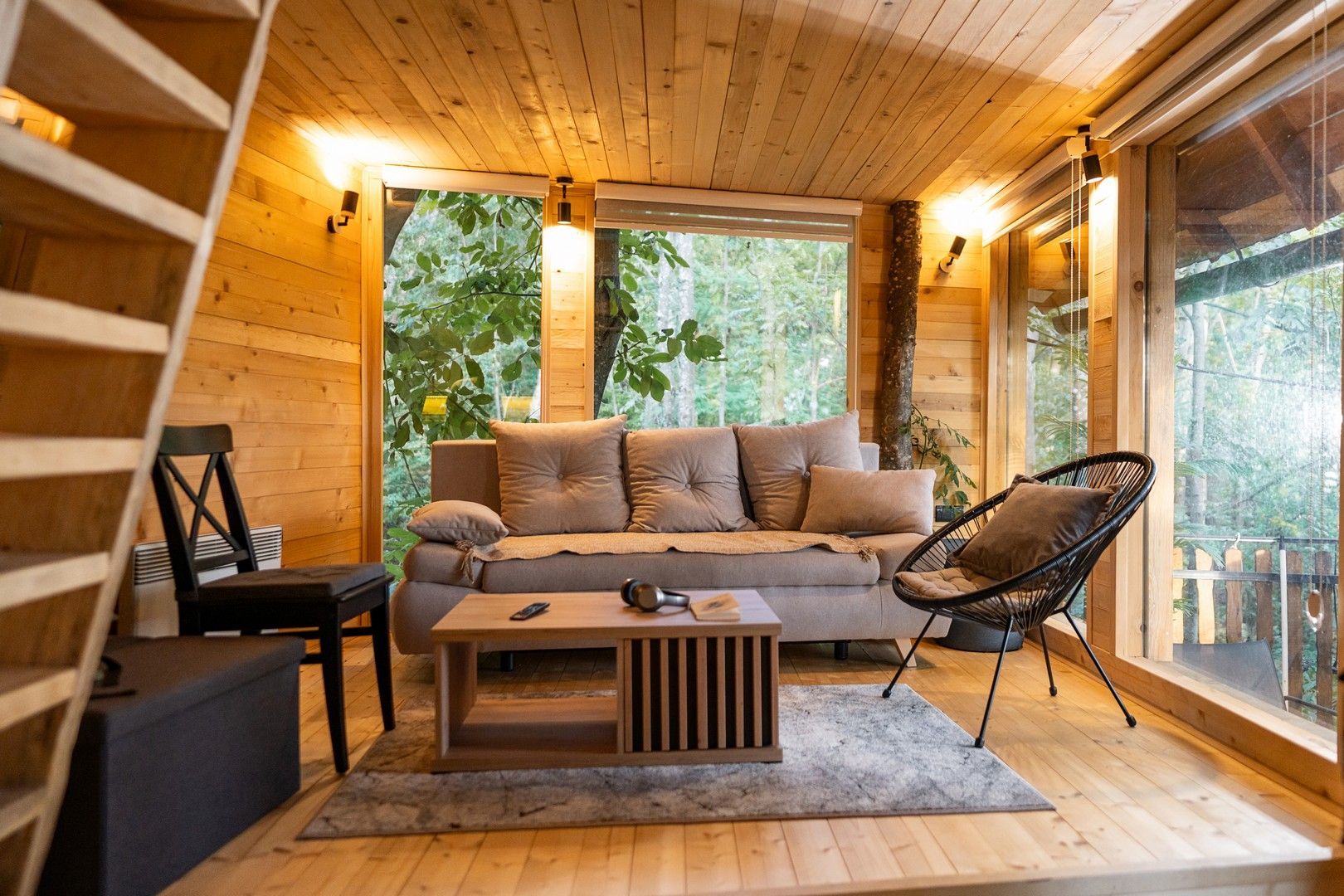 Un soggiorno con divano, tavolino, sedie e scale.