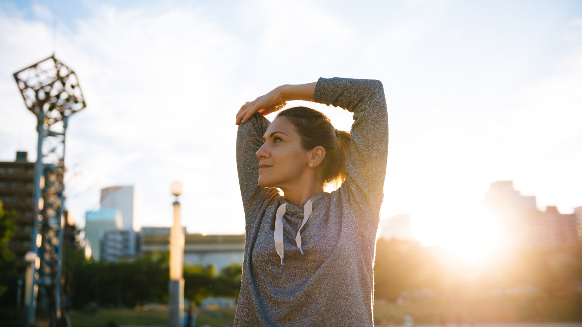 Woman embracing laughing man outdoors in sunlight.