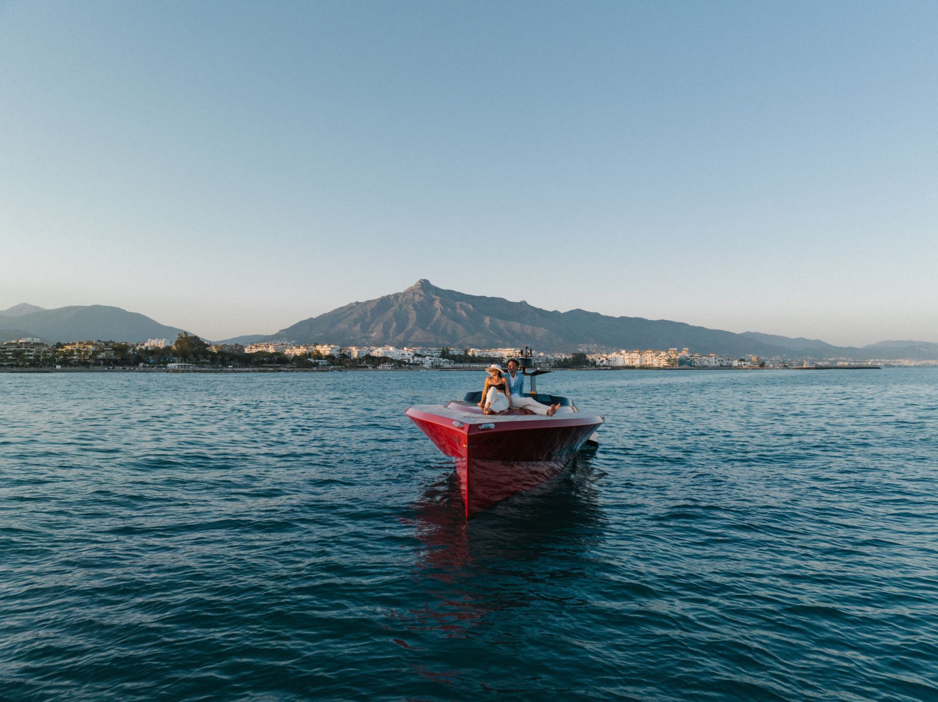 Red carbon fiber yacht cruising near Marbella with La Concha mountain in the background