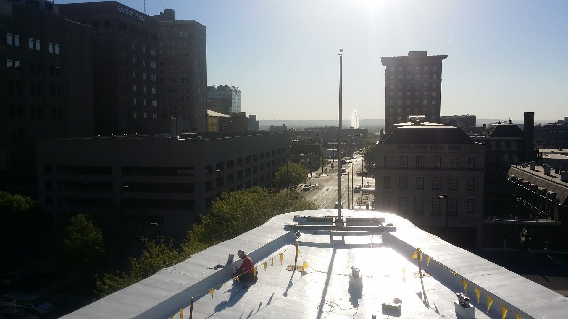 A person works on a flat white rooftop overlooking a city skyline at sunset.