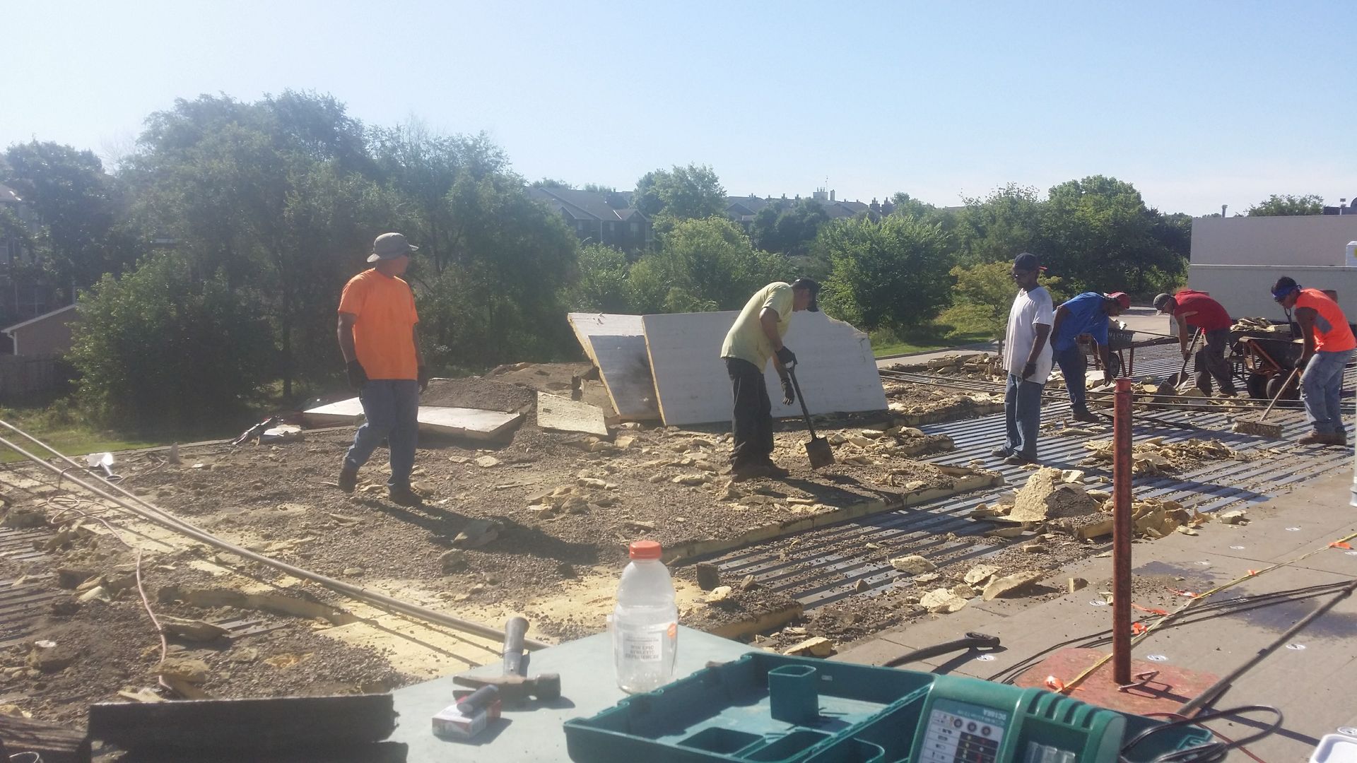 A group of workers in an outdoor, dirt construction site are installing dark-colored grid panels on the ground.