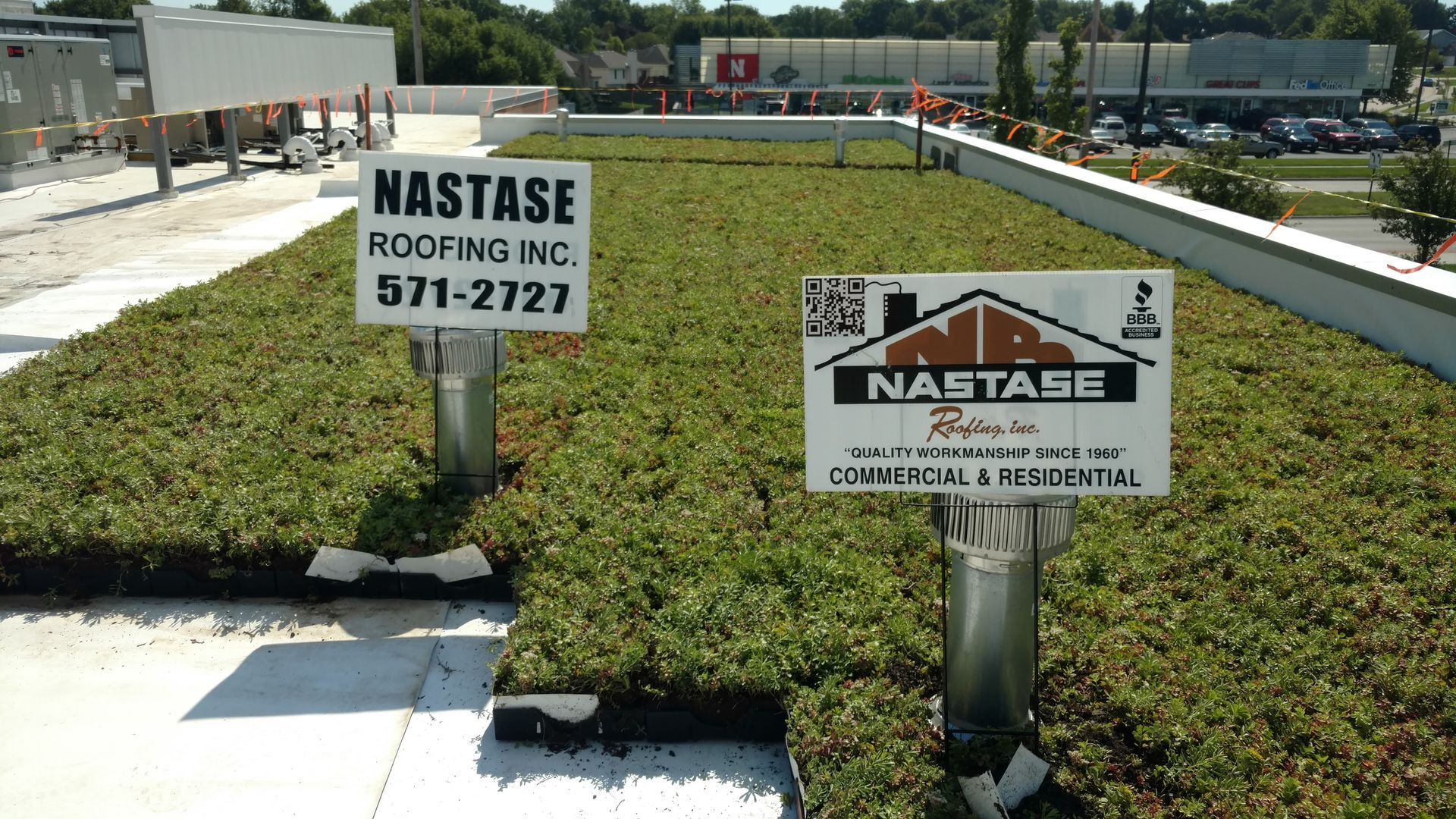 A rooftop garden installation with two Nastase Roofing Inc. signs standing in the center.