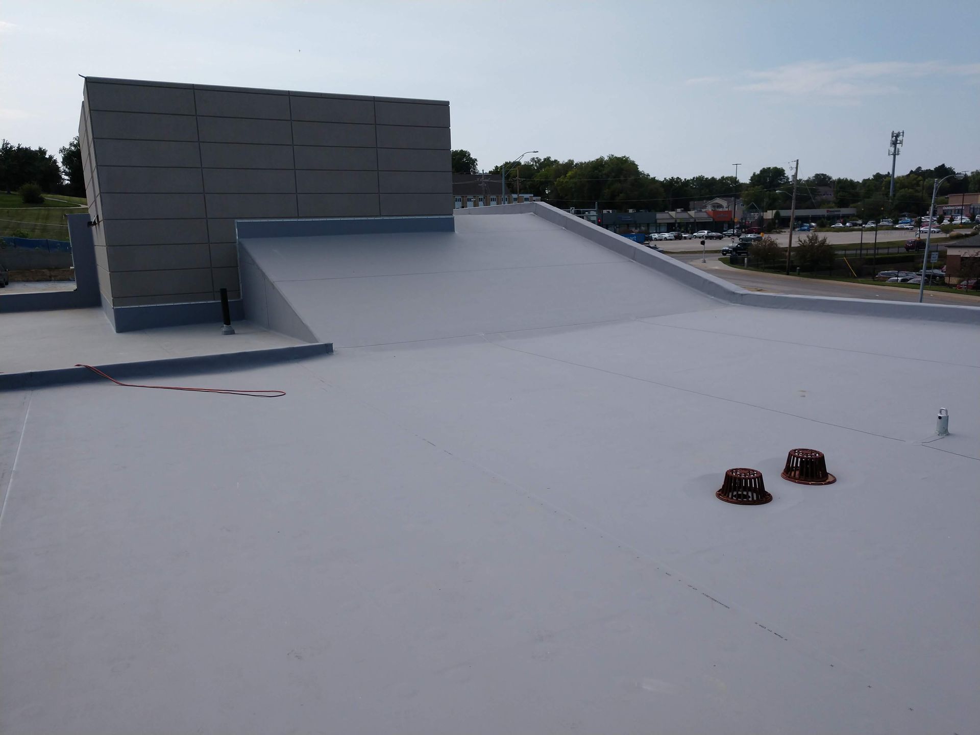 A flat grey roof with a sloped section leading up to a concrete block structure under a clear sky.