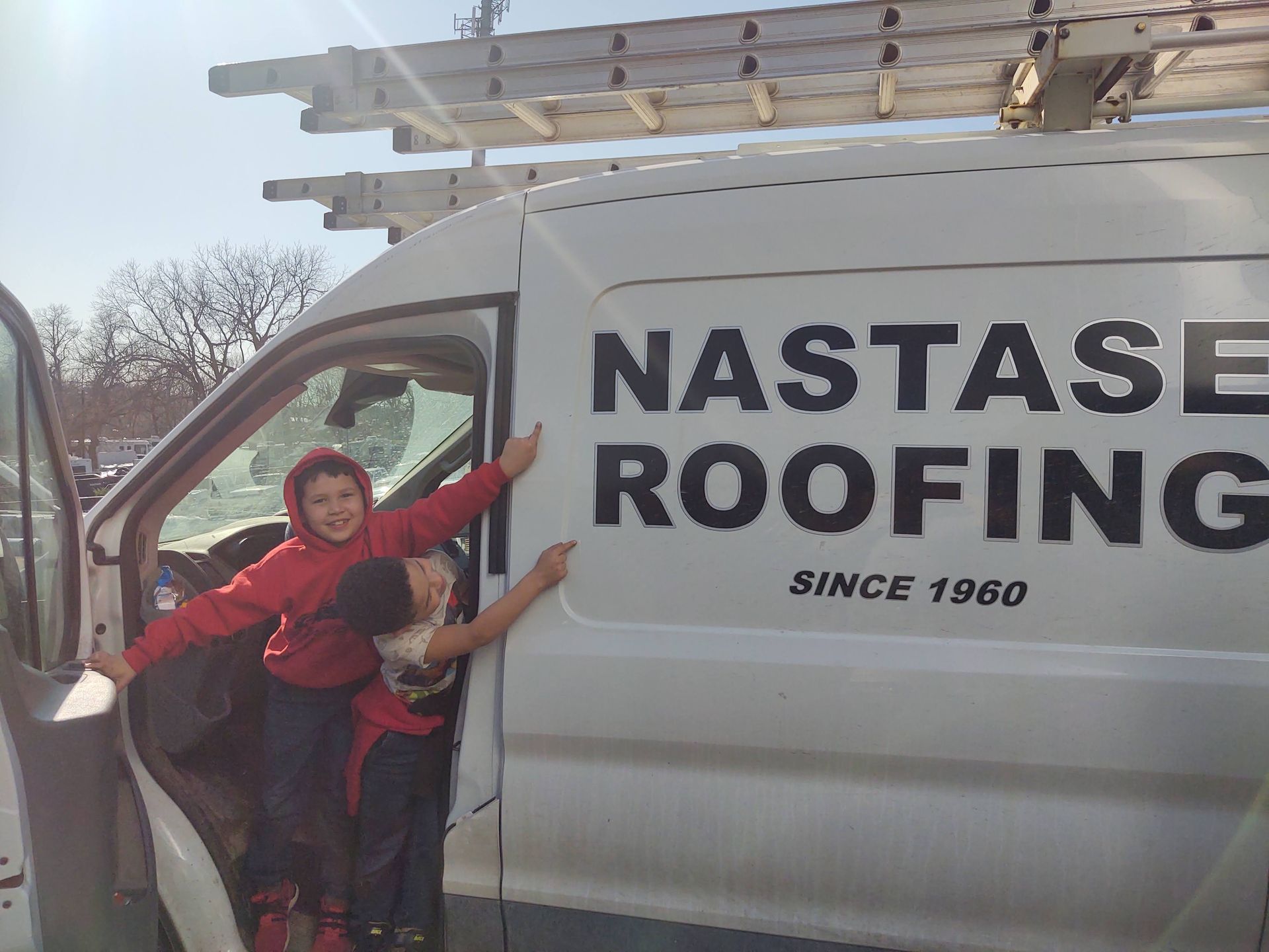 Two children lean against the side of a white van with 