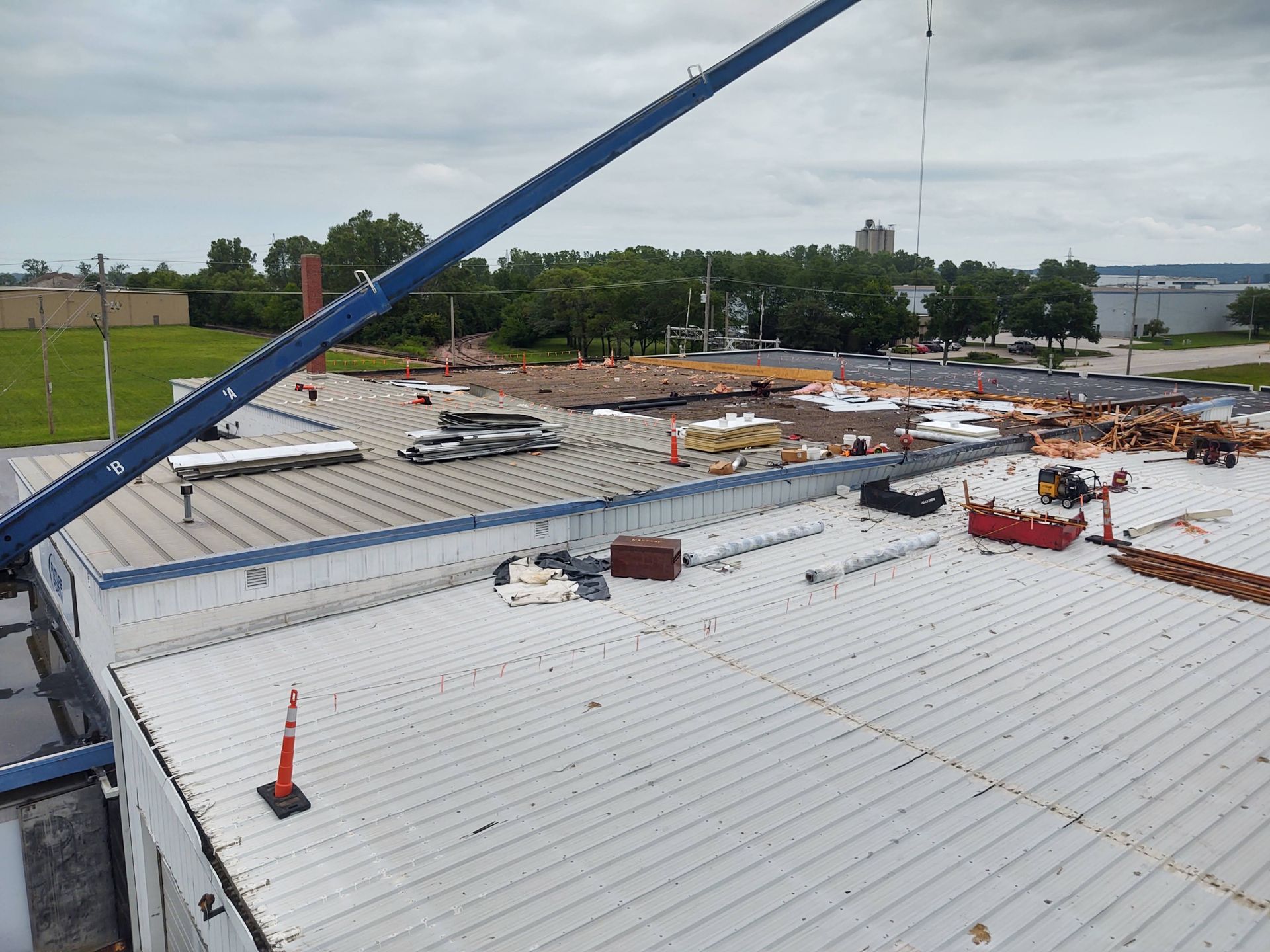 A view from a crane overlooking a flat building roof under repair with scattered debris and construction materials.
