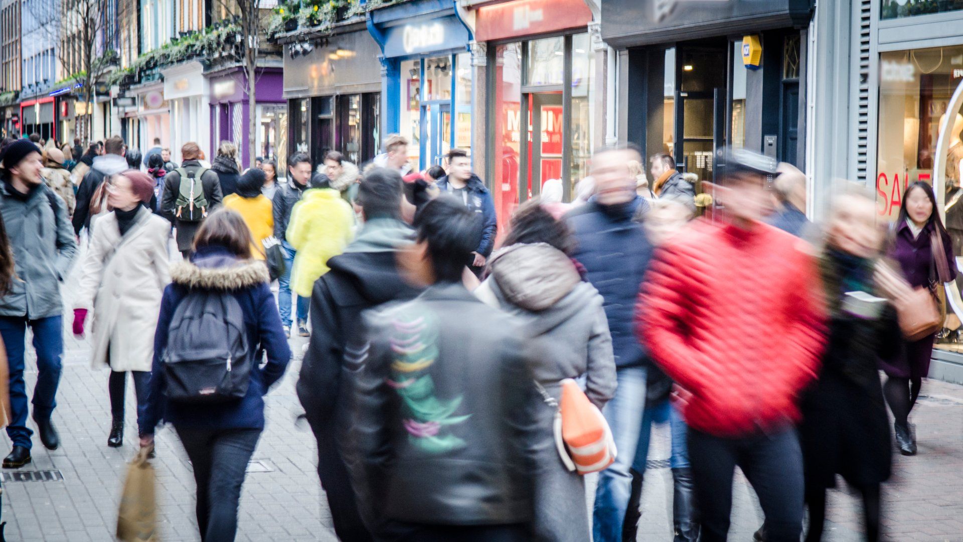 A crowd of people are walking down a busy city street.