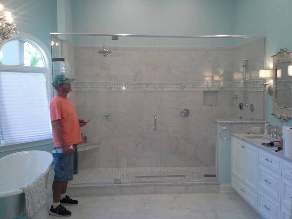Man in bathroom with finished shower, marble tile, and vanity.