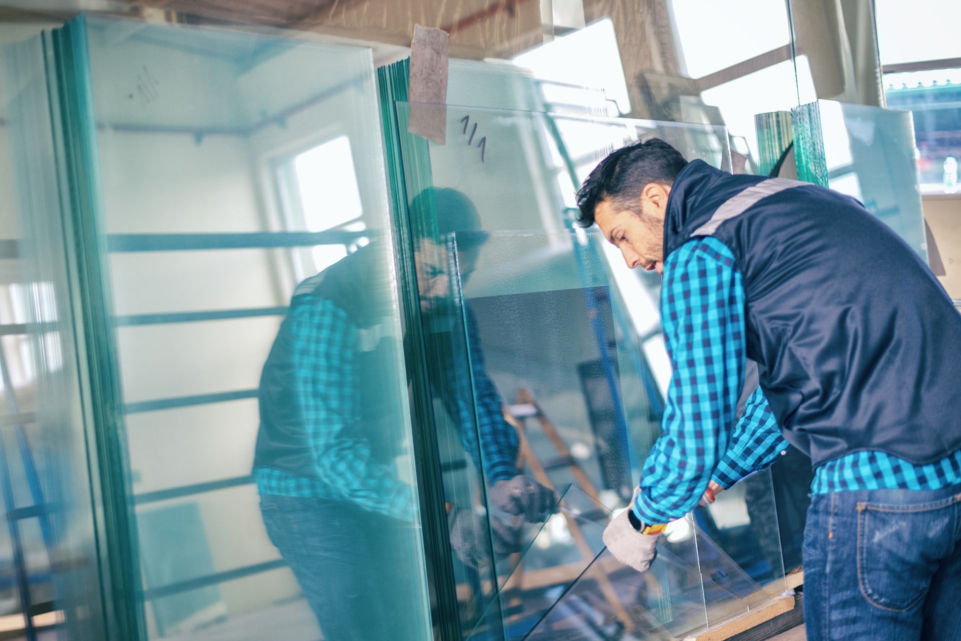Worker handling large glass panels in an indoor workshop setting.