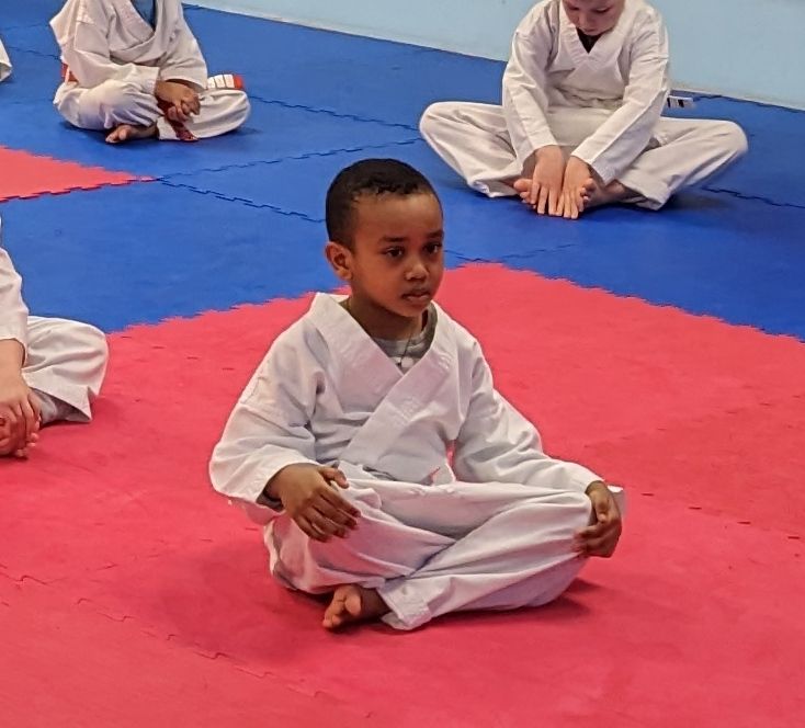 Two young boys are practicing martial arts in a dark room.