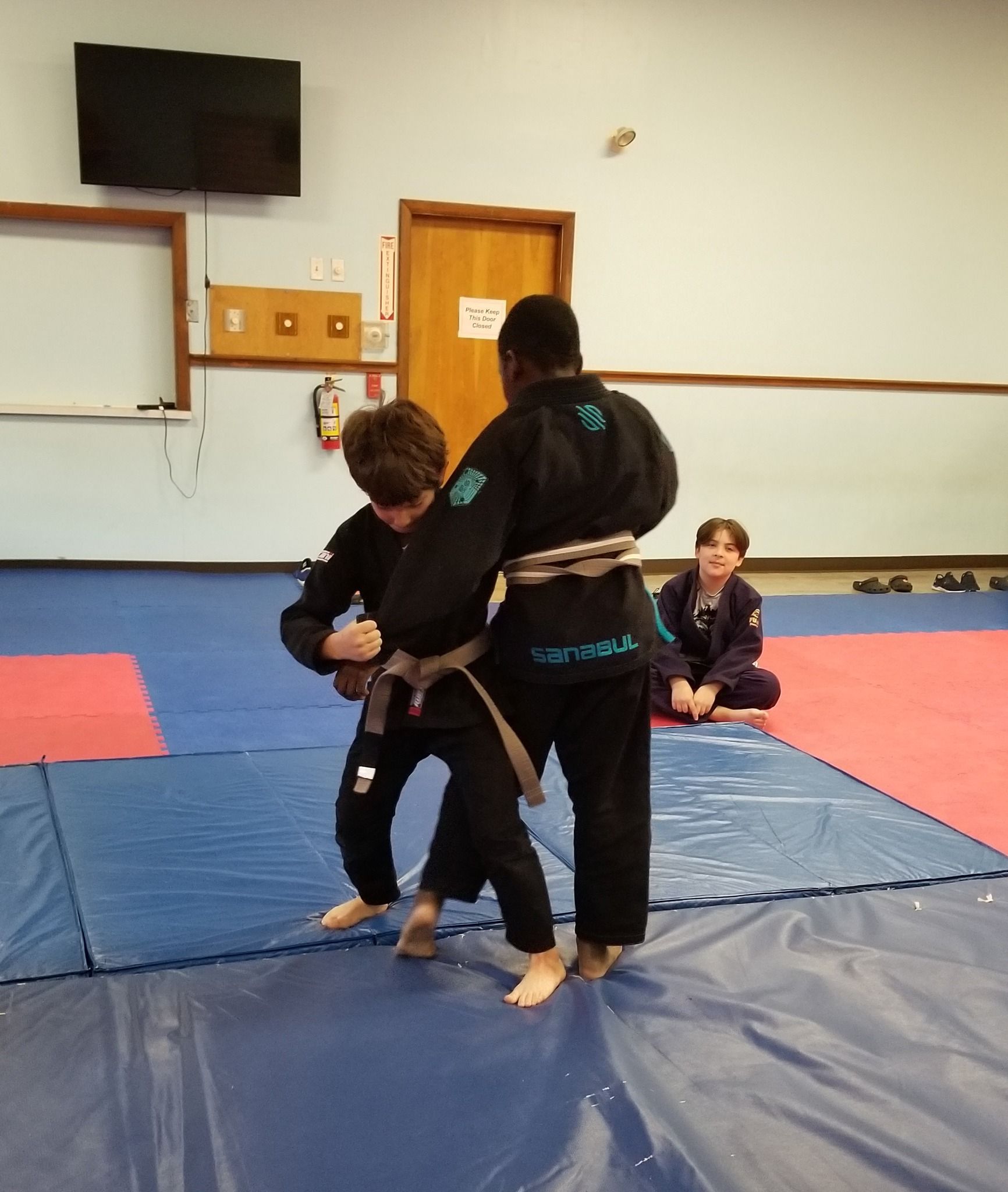 a person with a yellow belt is laying on another person 's back