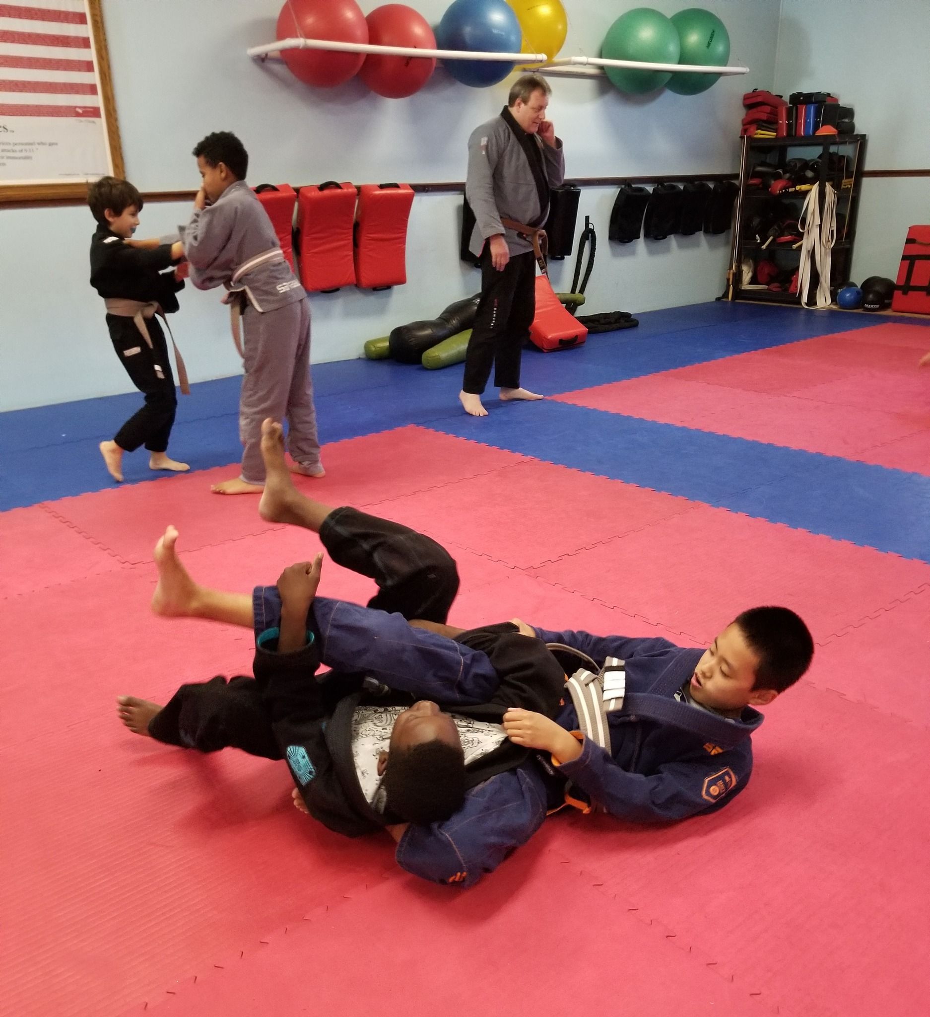 Two boys are wrestling on a mat in a gym.
