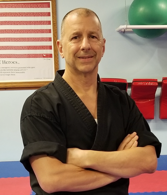 a man in a black karate uniform with his arms crossed