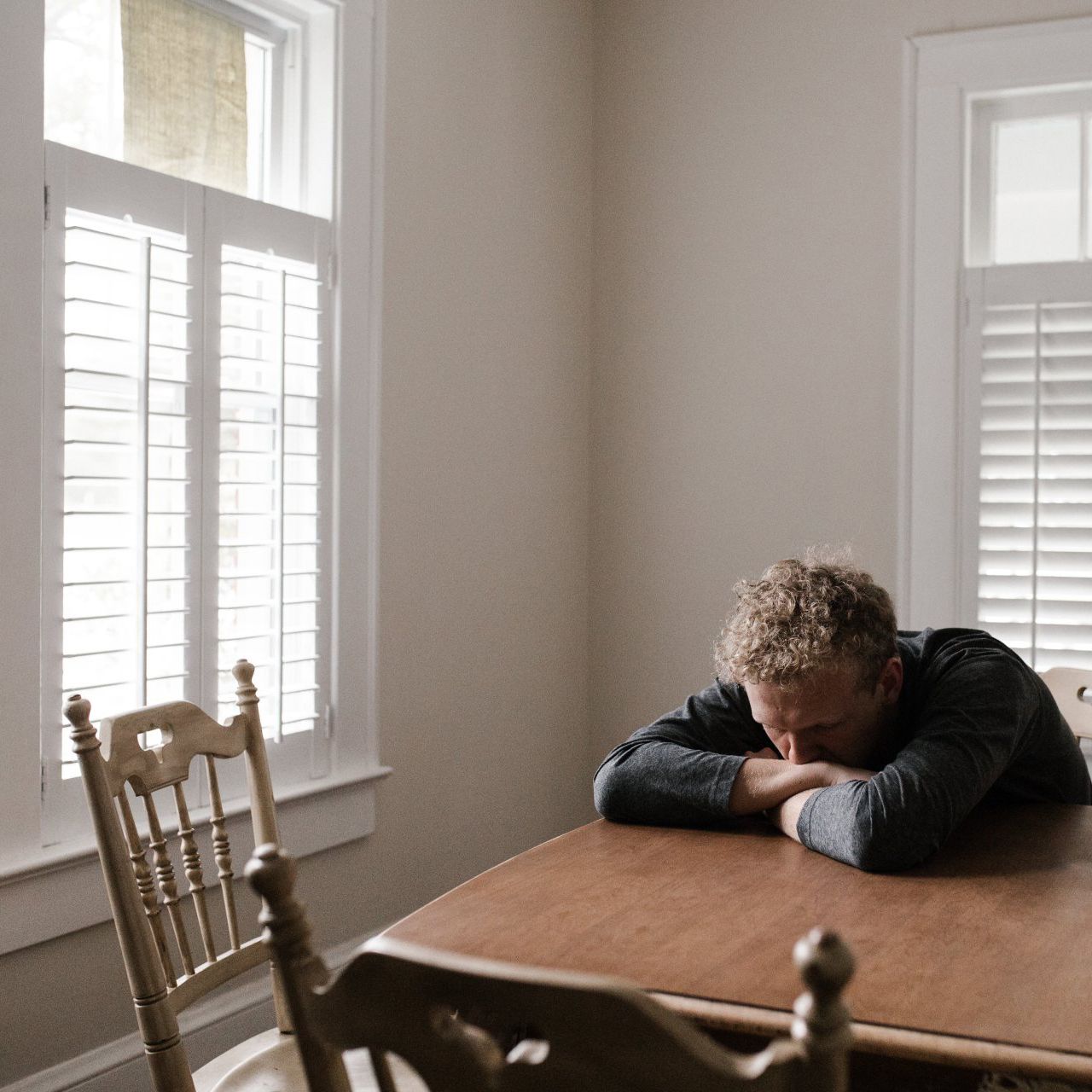 a man is sitting at a table with his head resting on his hands