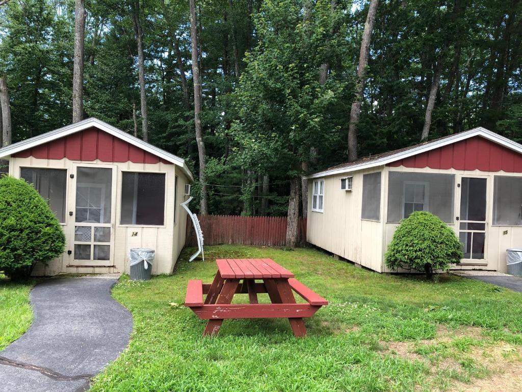 Two small houses with screened in windows and a picnic table in front of them.