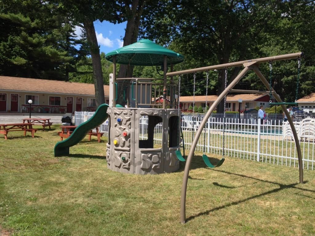 A playground with a slide and swings in a grassy area.