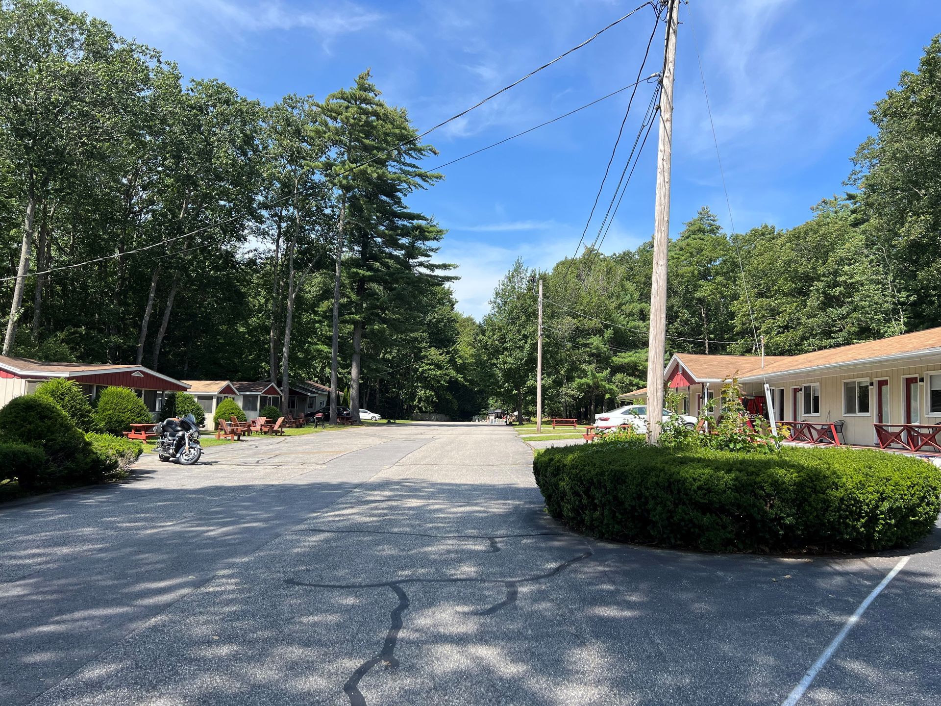 A motel is surrounded by trees and bushes on a sunny day.
