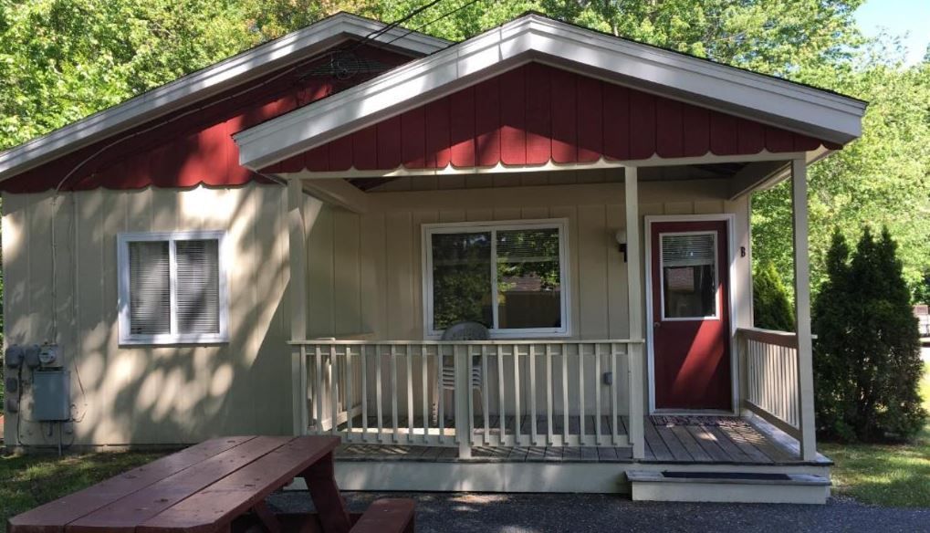 A small house with a porch and a picnic table in front of it.