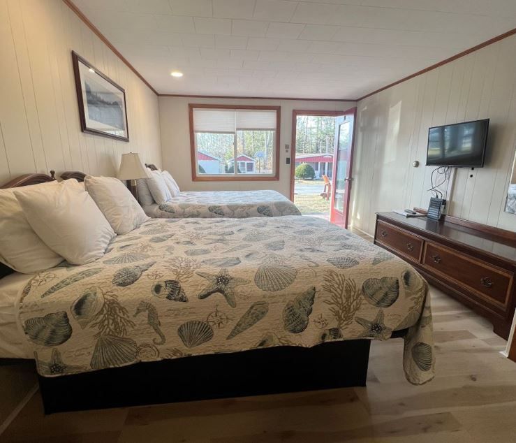 a hotel room with two beds and a flat screen tv .