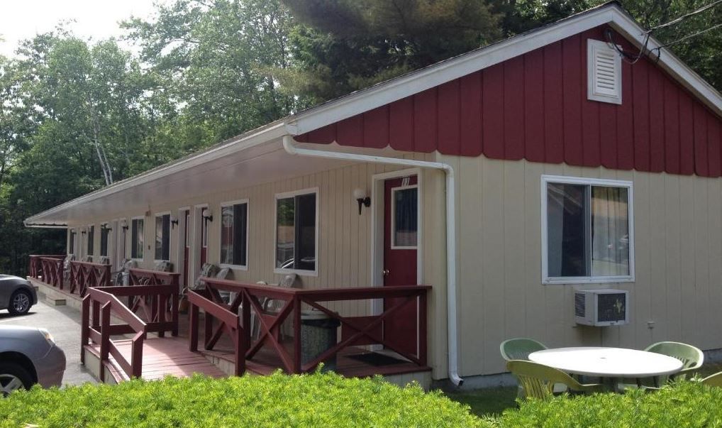 A small house with a red roof and a table and chairs in front of it.