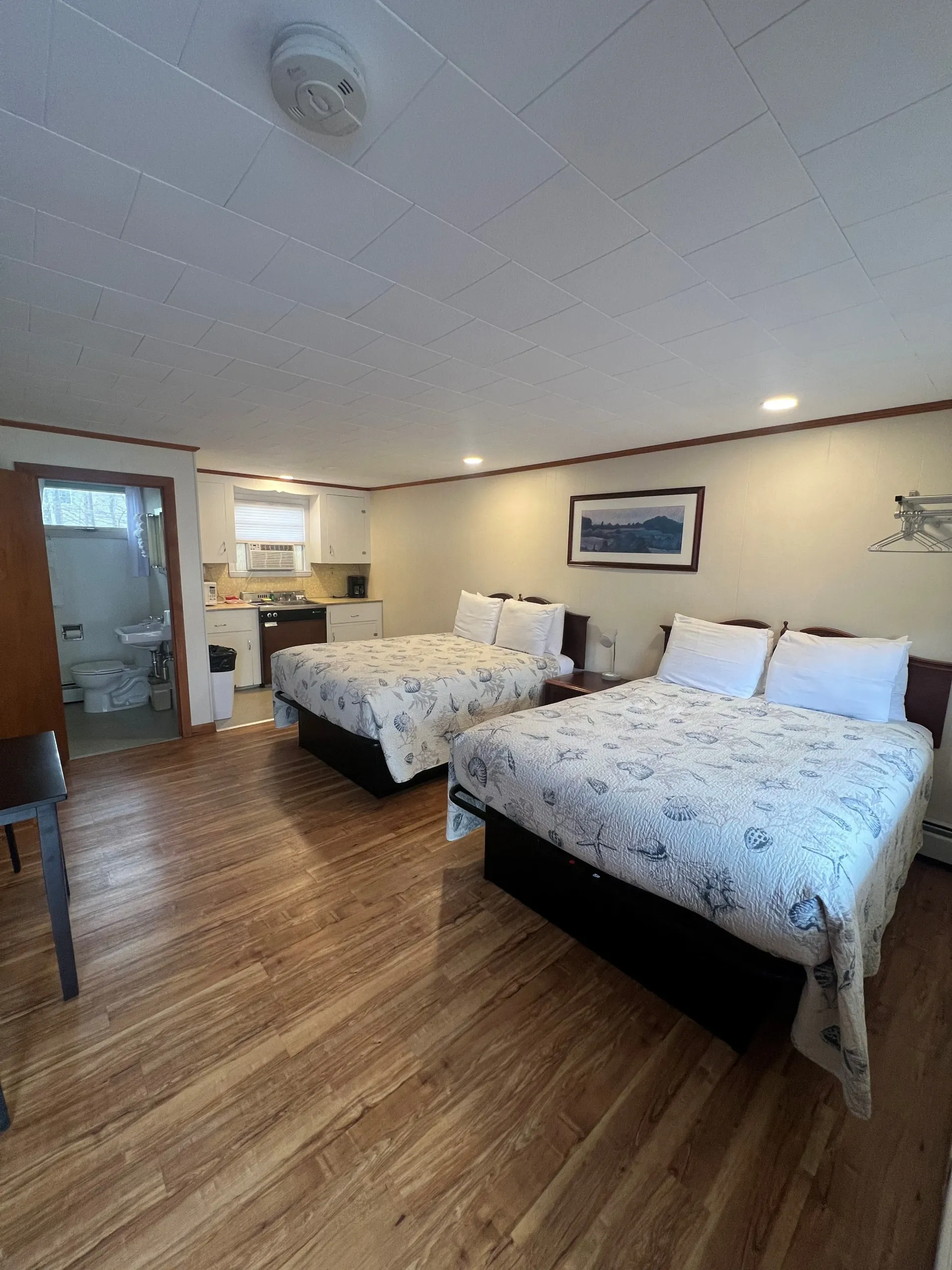 A hotel room with two beds and a kitchen.