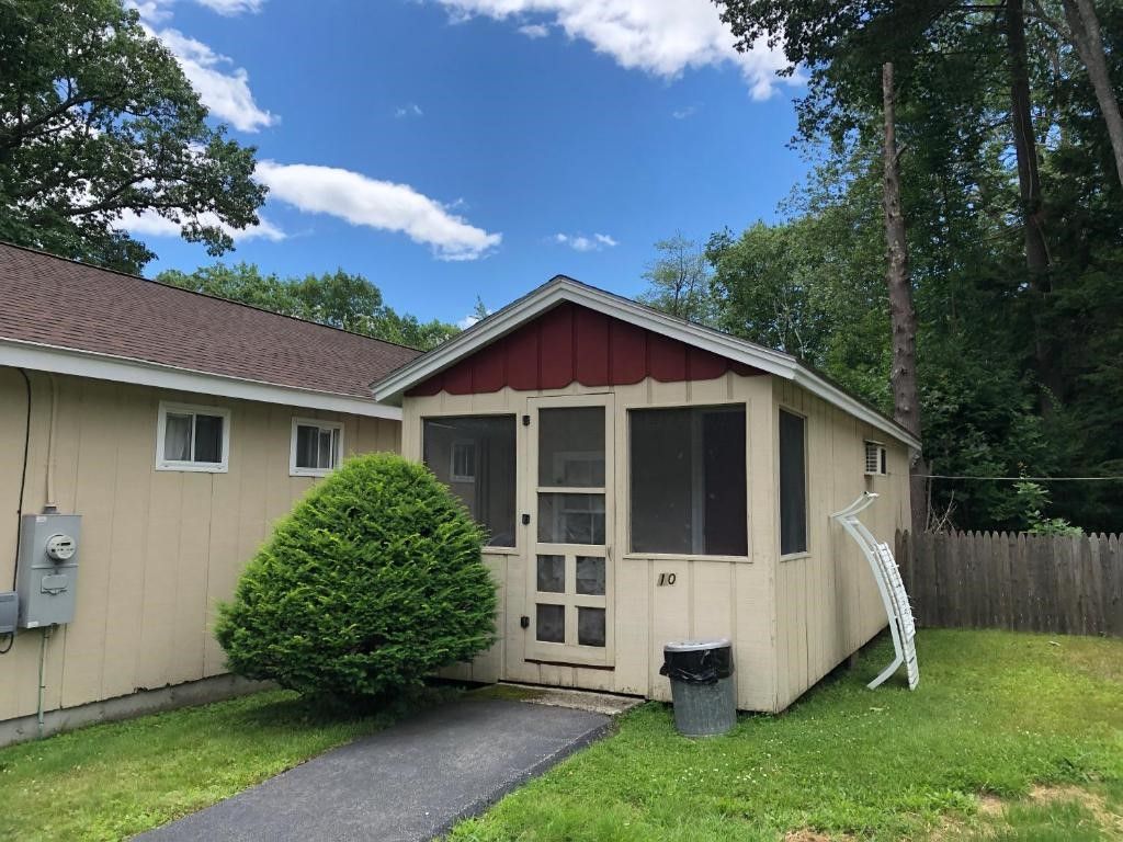 A small house with a screened in porch in front of it