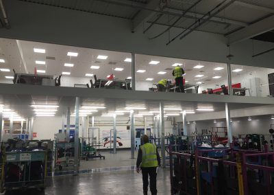 Interior warehouse with a mezzanine level, workers, and equipment.